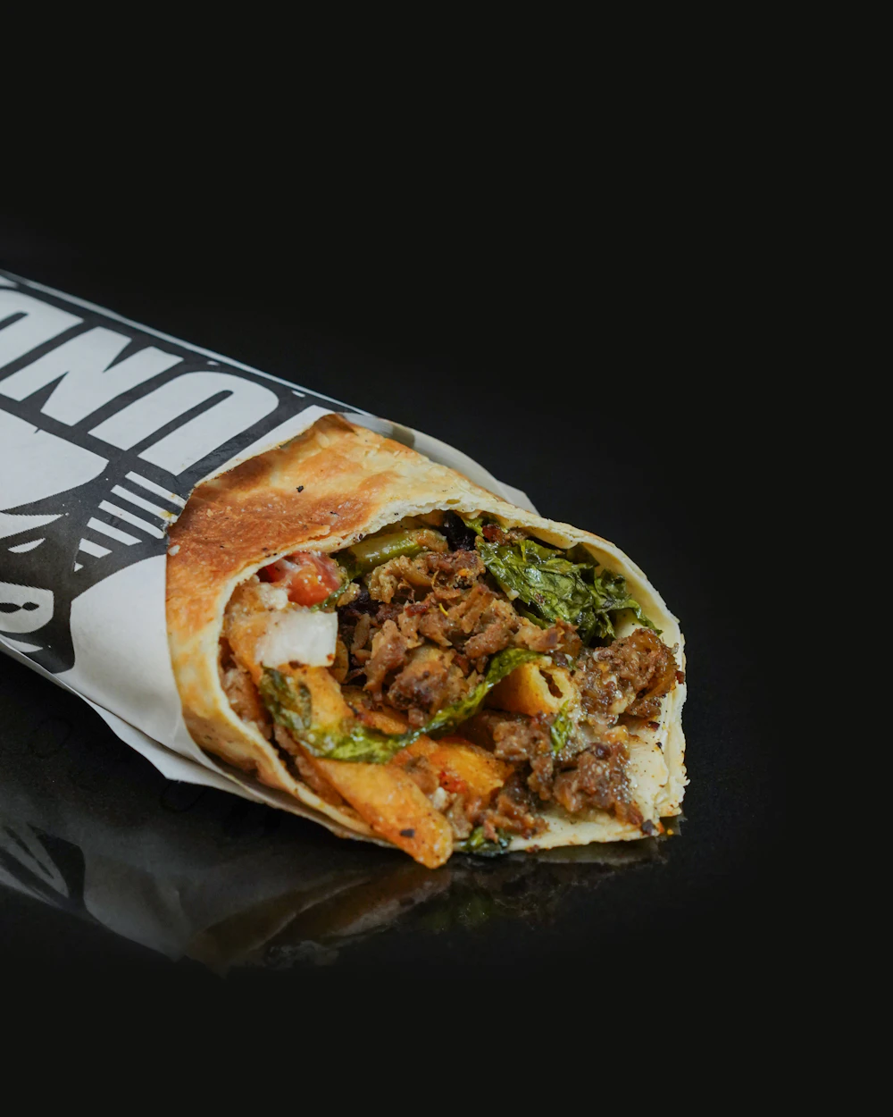 Kebab enrollado en pan, relleno de carne, verduras y salsa